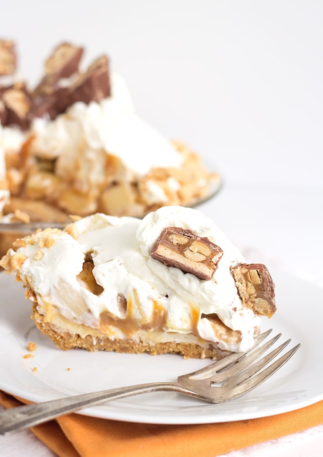 Snickers Caramel Apple Pie - delicious layers of cream cheese, caramel, crunchy, fresh apples and whipped cream. Best of all, it's topped with Snickers and peanuts. It's a quick and easy dessert too!