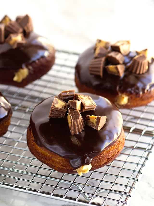 Chocolate Glazed Peanut Butter Filled Donuts - fried donuts filled with a peanut butter frosting, topped with a milk chocolate ganache and finished with some peanut butter cups. 