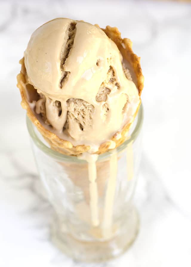 melting sweet tea ice cream in a cone sitting in glass with drips running down it